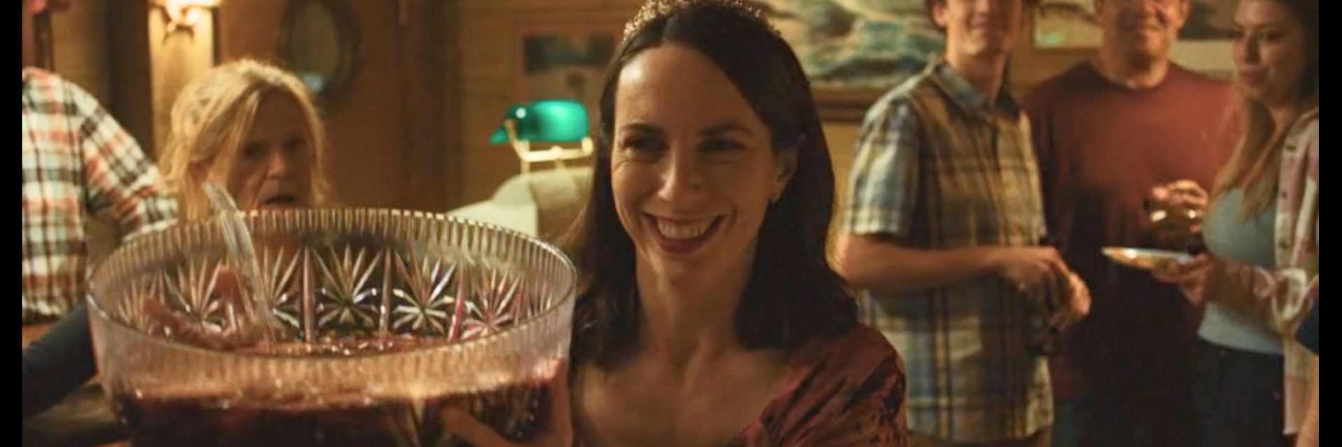 woman in red dress and tiara smiling as its time to serve punch at a partym