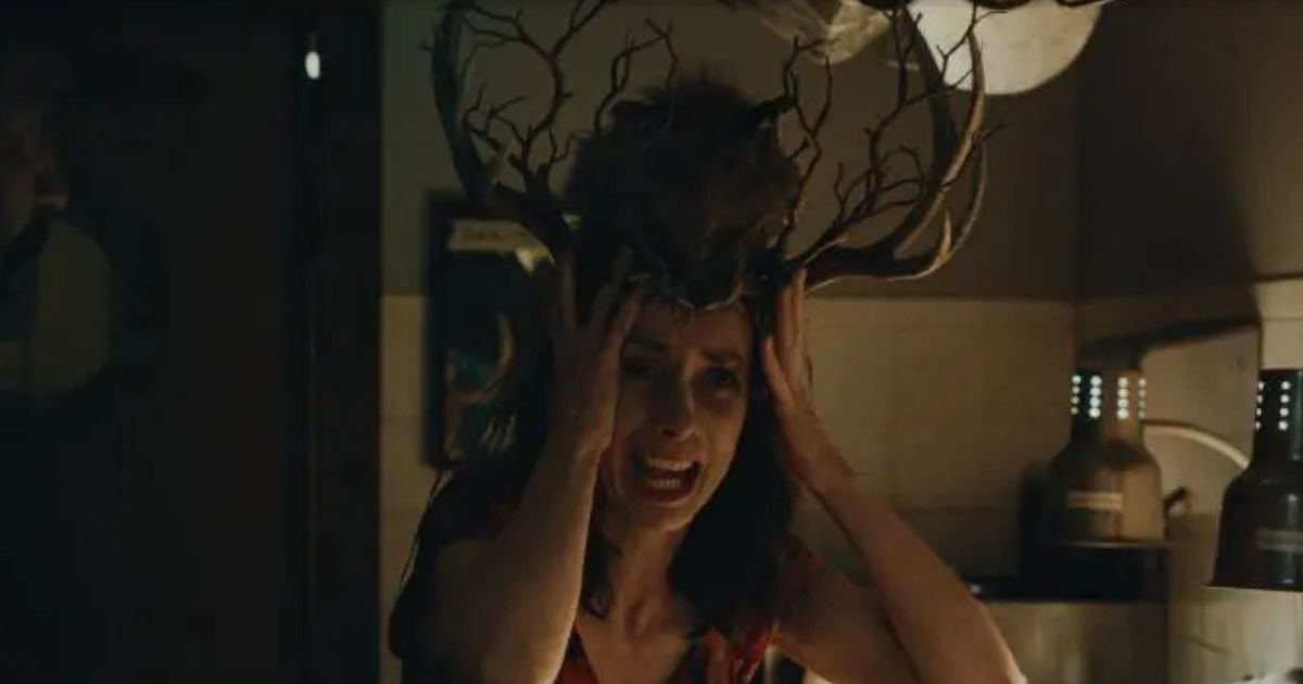 woman holding hands to head with antlers