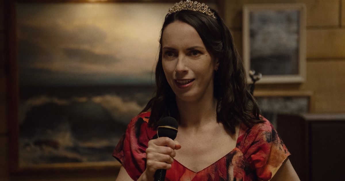 woman in red dress and tiara smiling holding a microphone