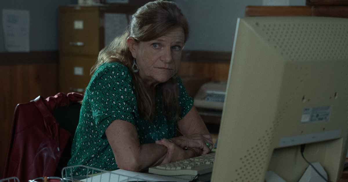 woman in green shirt sitting at her desk with her computer