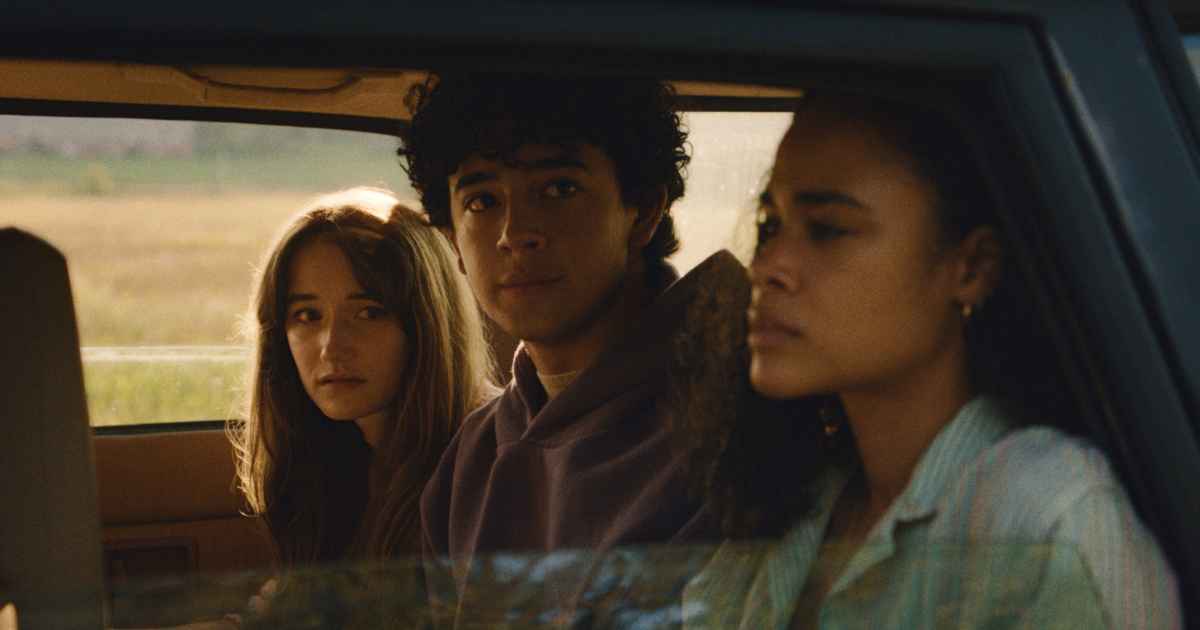 three teenagers two females and one male sitting in a car