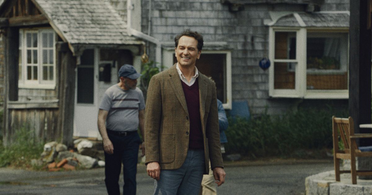 man in blazer and sweater outside in a new england town