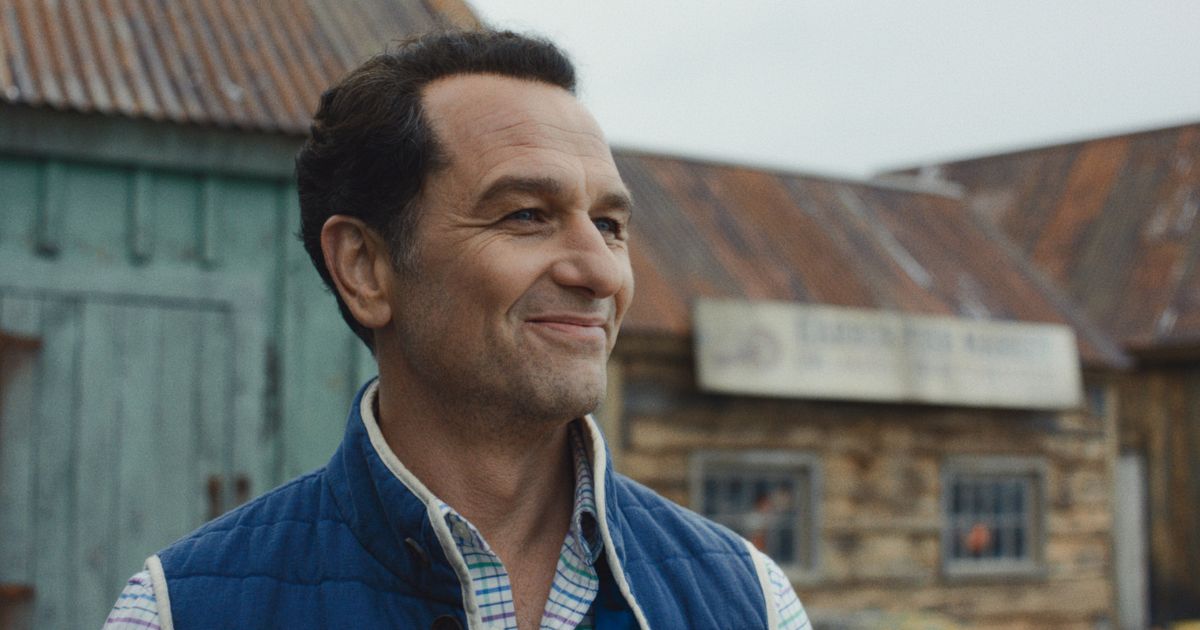 man in blue vest and plaid shirt looking proud